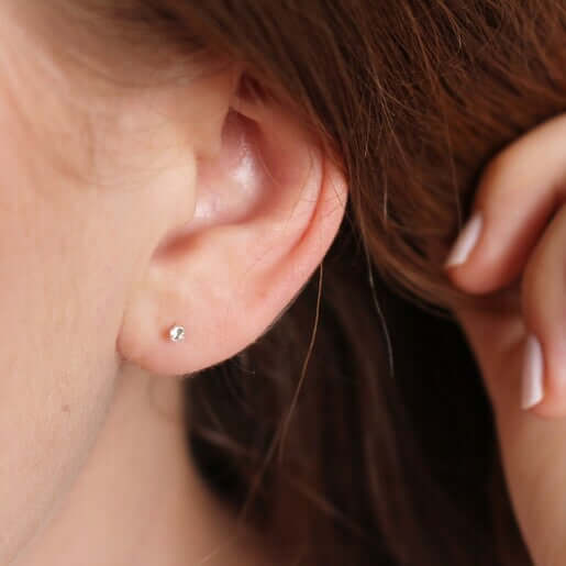A woman's ear adorned with a Jadore Jewelry diamond stud earring.