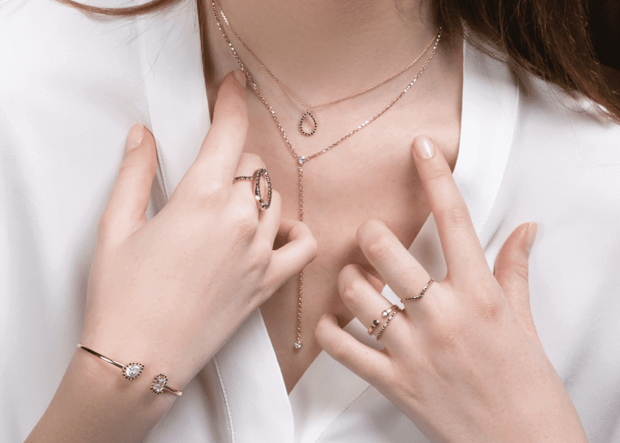A woman is posing with a minimalist necklace, ring, and bracelet.