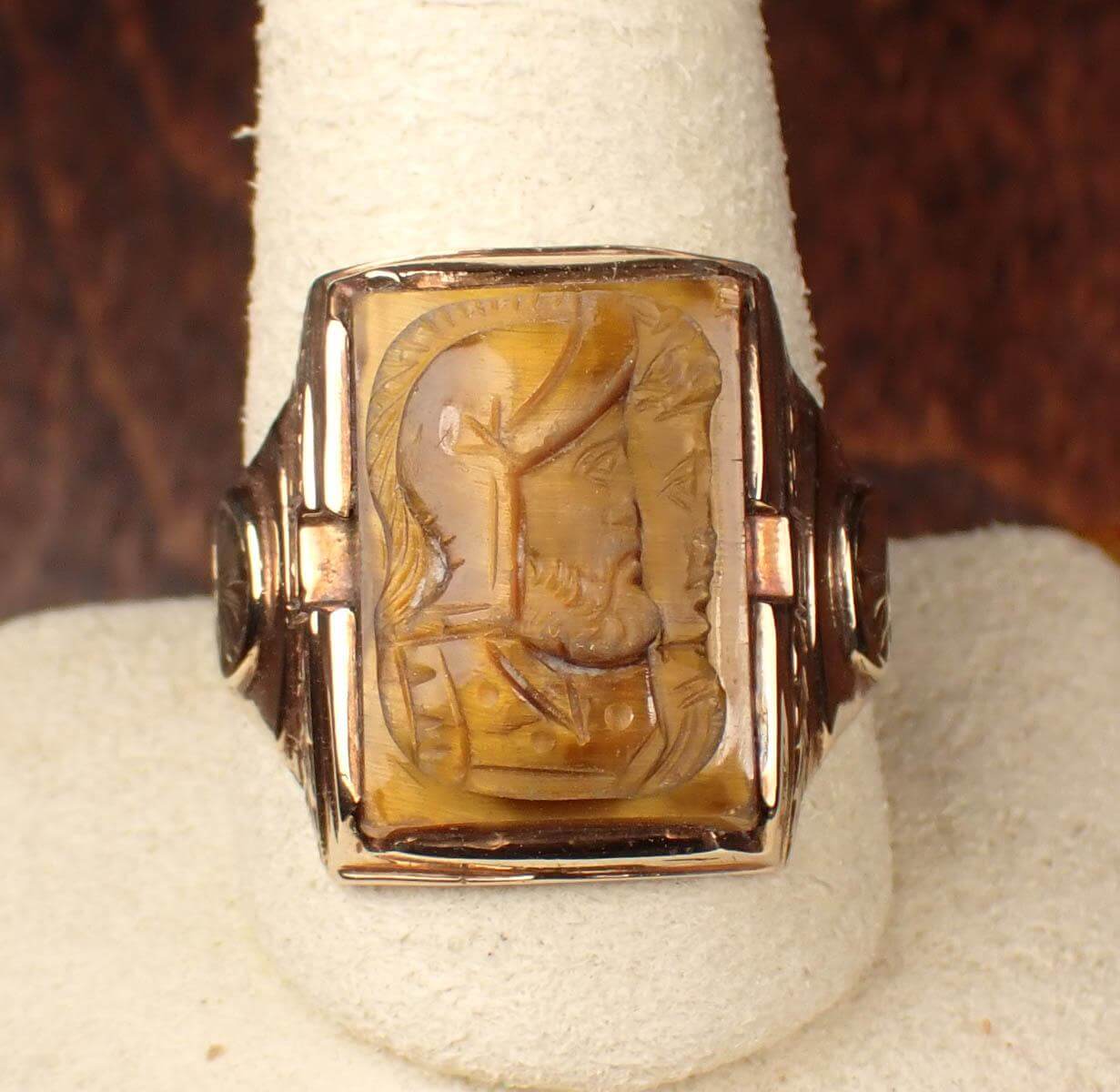 A gold ring with a carving of a man and a woman. - tigers eye roman soldier ring