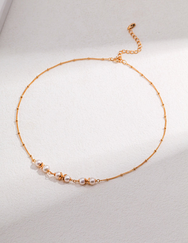 An 18K gold plated Whispering Pearls Necklace adorned with white beads.