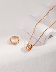 A Harper's Pearl Wheel Necklace and ring set on a white surface.