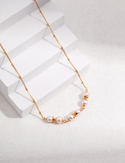 The Whispering Pearls Necklace is a stunning piece of jewelry crafted from 18K gold. The delicate Whispering Pearls Necklace features beautiful pearls elegantly placed on top of a pristine white piece of paper.