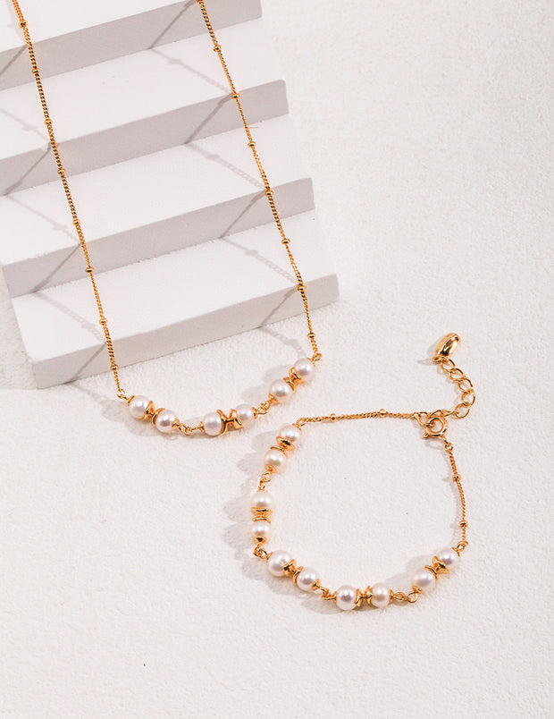 The Whispering Pearls Necklace is an exquisite set that includes both the Whispering Pearls Necklace and bracelet, adorned with lustrous pearls. Crafted from 18K gold, this stunning jewelry piece