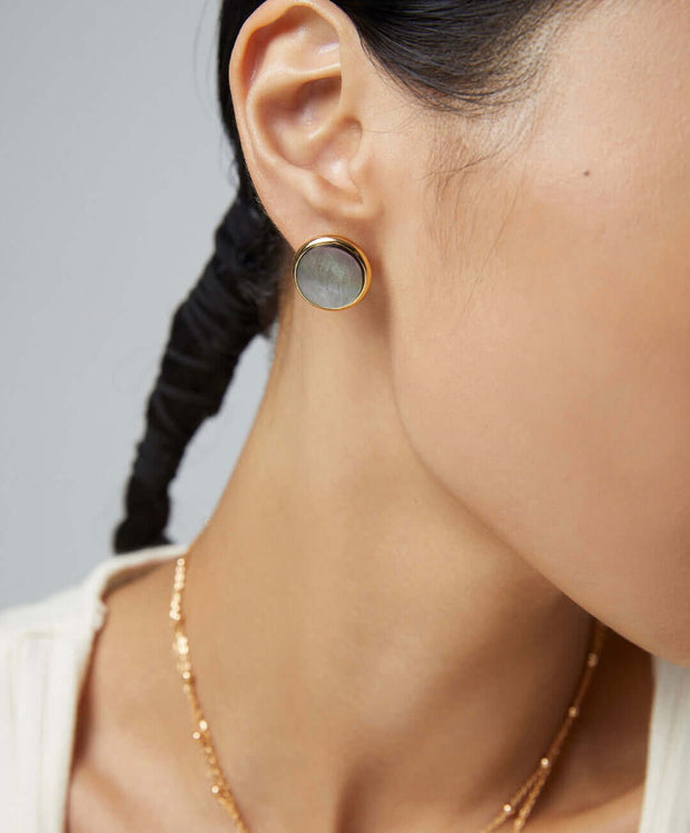 A woman wearing Eclipse Earrings with a natural black pearl.