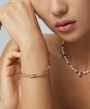 A woman showcasing her style with a Bamboo Bangle and pearls jewelry.