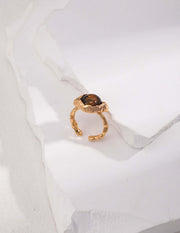 An adjustable size Tiger's Eye Ring featuring a black stone on top, with a lustrous 18K gold plating.