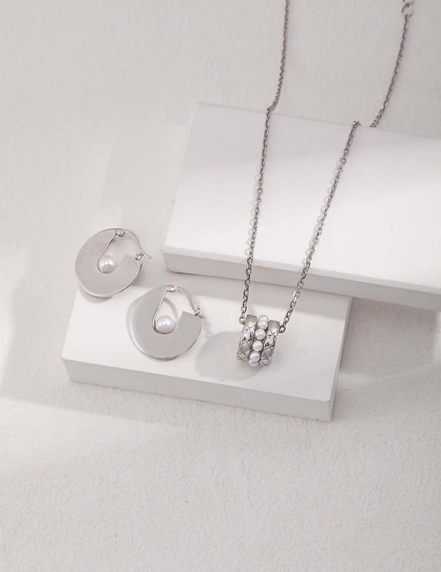 A Harper's Pearl Wheel Necklace and earring set on a white table.