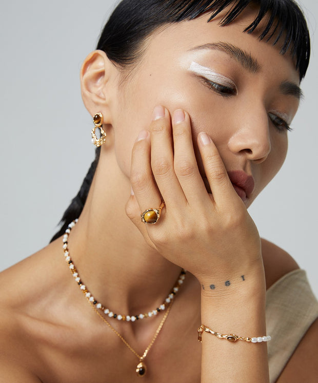 A woman wearing 18K gold plated Tiger's Eye pearls and a Tigerite bracelet.