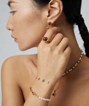 A woman wearing an exquisite Tiger's Eye Pearl Bracelet and a stunning pearl necklace.