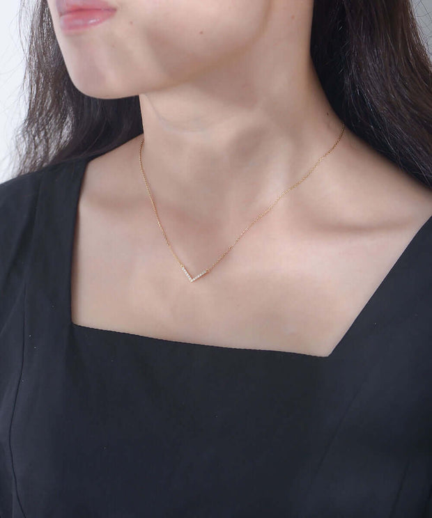 A woman elegantly adorned with a Valentina Necklace, an exquisite and timeless statement piece, is the perfect embodiment of style and sophistication.