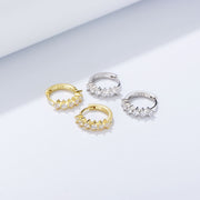 Three stylish Venus Huggie Hoop Earrings adorned with diamonds - perfect for a work ensemble.