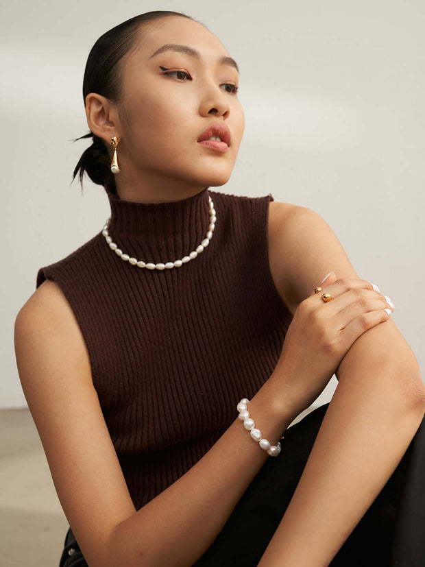 A woman wearing a18K Gold-Plated turtle neck sweater and Baroque Pearl Bracelet.