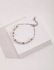 A Whispering Pearls Bracelet adorned with delicate beads on a white surface.