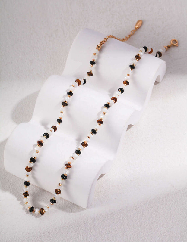 A Tigerite Charm Choker necklace with tiger eye beads on top of a white background.