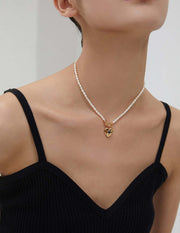 A woman wearing a black top and a Noir Heart Agate Pearl Necklace, crafted in Sterling Silver.