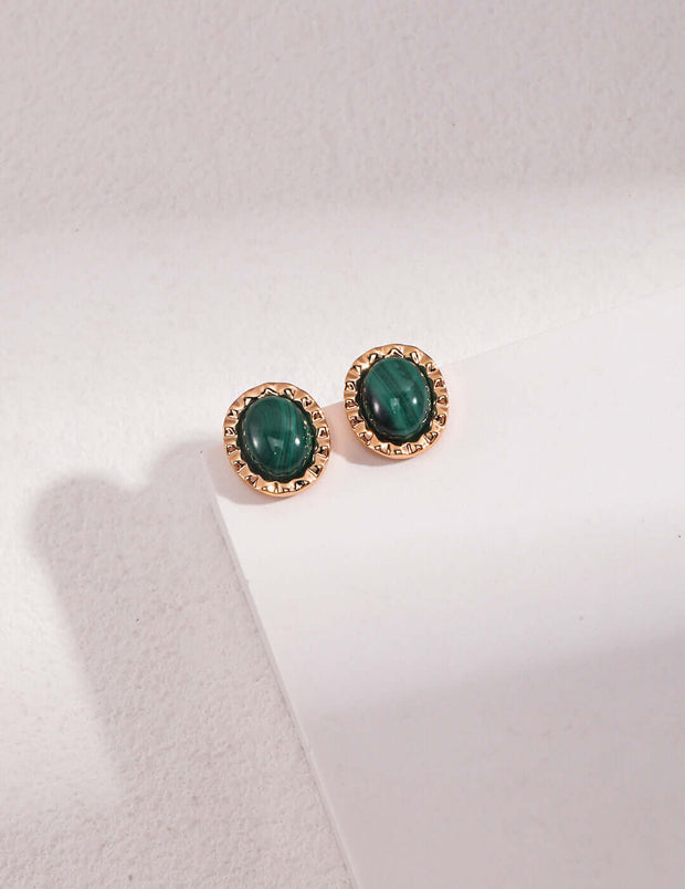 A pair of Peacock Stud Earrings on top of a white surface.