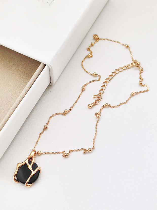 A natural black agate necklace with a gold stone on it. This exquisite piece of jewelry features 18K gold plating and showcases a stunning black stone.