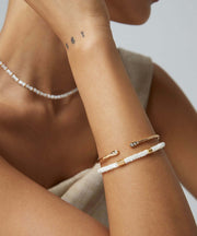 A woman adorning a Minimalist Chic Bangle with a timeless white and gold bangle.