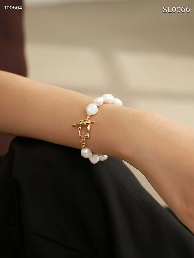 A woman wearing a Baroque Pearl Bracelet with a gold clasp and pearls.