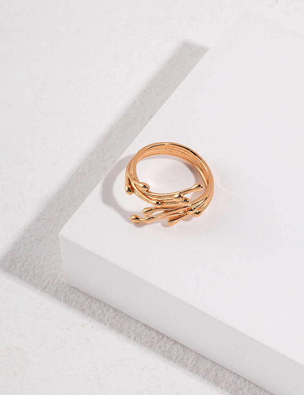 The Ethereal Twig Ring, an 18k gold plated silver wardrobe staple, is resting on a white surface.