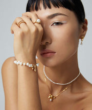 A woman wearing a Golden Heart Pearl Bracelet and pearl necklace.