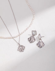 A fashionable silver Natural Pearl Double Layered Necklace and earrings set showcasing a natural pearl on a white surface.