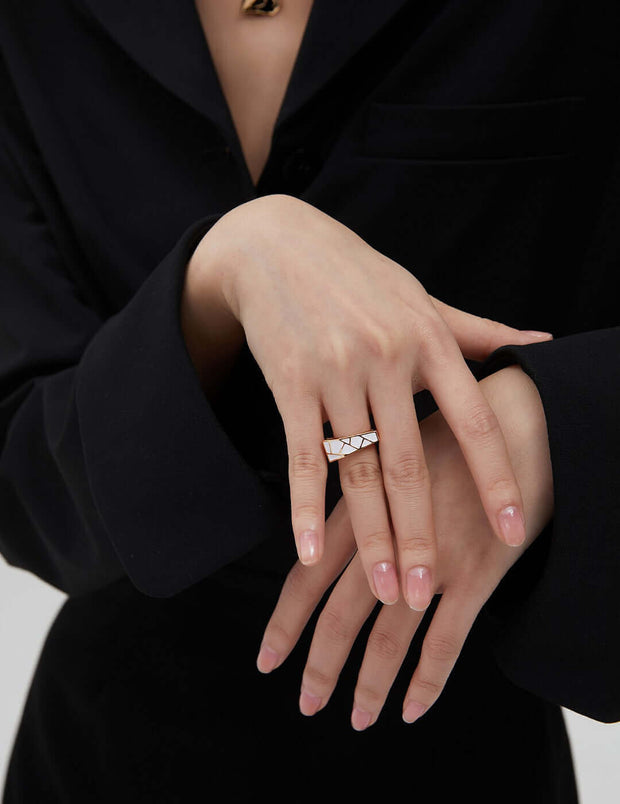 A woman wearing a Modernist Contrast Ring on her hand, enhancing the unique design of her chic black suit, resulting in an eye-catching ensemble.