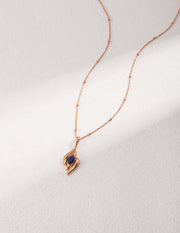 The Lazurite Antiquity Necklace features the Lazurite Antiquity Necklace, a sapphire stone suspended from a gold chain, adding a touch of stylish sparkle to any ensemble.